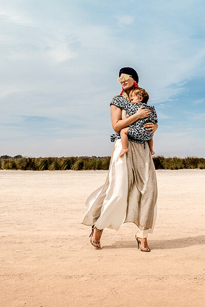 Model steht mit einer Fidella Babytrage im Leopardendesign in der Wüste